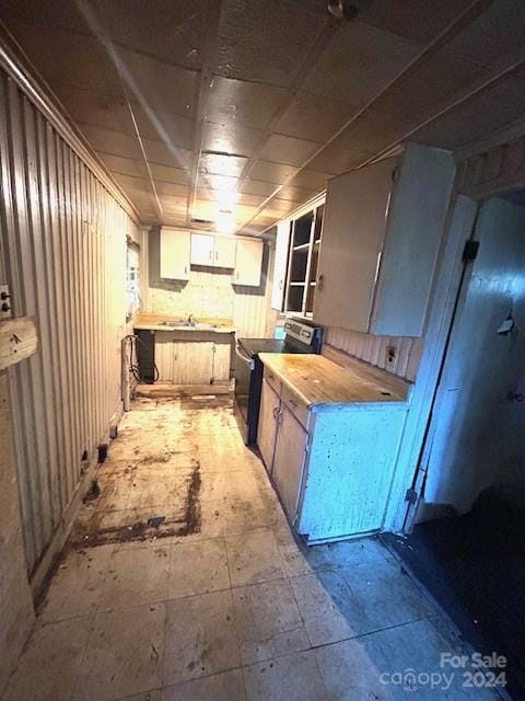 kitchen with wooden counters, sink, and black electric range oven