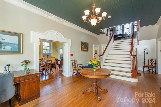 entrance foyer with hardwood / wood-style floors, ornamental molding, and a notable chandelier