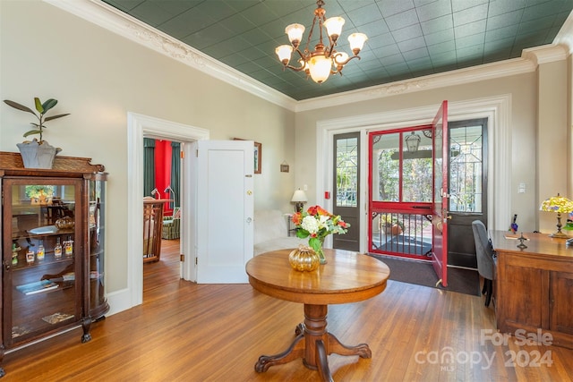 interior space with hardwood / wood-style floors, ornamental molding, and a notable chandelier