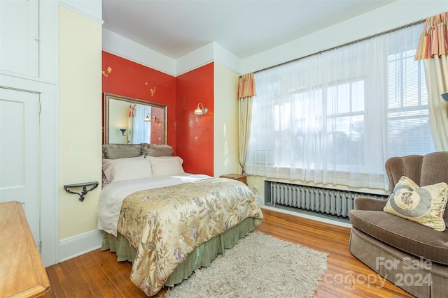 bedroom with radiator heating unit and hardwood / wood-style flooring