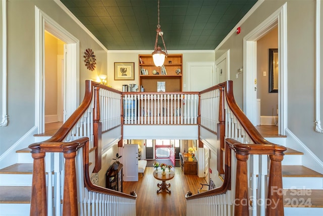 stairs with hardwood / wood-style floors and crown molding