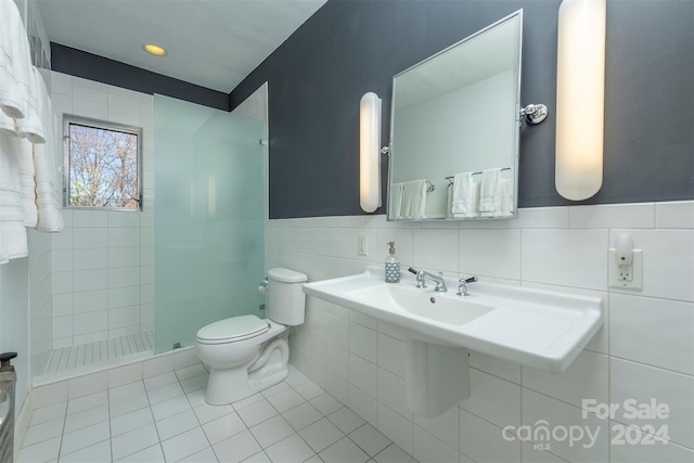 bathroom featuring a tile shower, toilet, tile walls, and tile patterned flooring