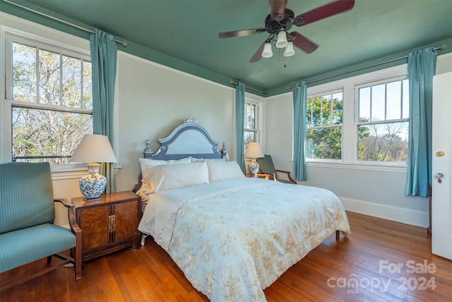 bedroom featuring wood-type flooring, ceiling fan, and multiple windows