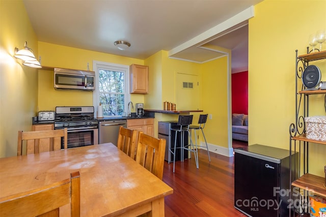 kitchen with dark hardwood / wood-style flooring, sink, light brown cabinetry, and appliances with stainless steel finishes