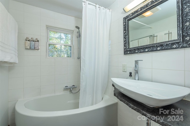 bathroom with shower / bath combination with curtain, sink, and tile walls