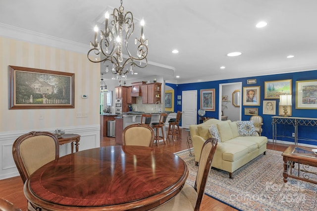 dining room featuring light wood-type flooring, crown molding, and an inviting chandelier