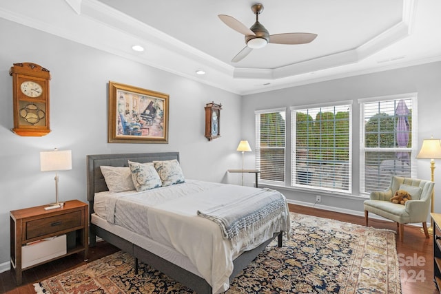 bedroom with dark hardwood / wood-style flooring, ornamental molding, ceiling fan, and a raised ceiling