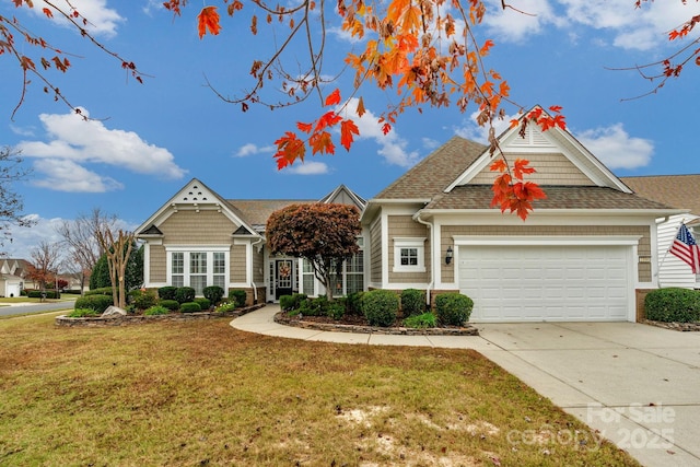 view of front facade featuring a shingled roof, a front yard, driveway, and an attached garage