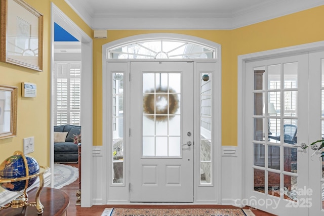 foyer entrance with wainscoting, crown molding, and wood finished floors