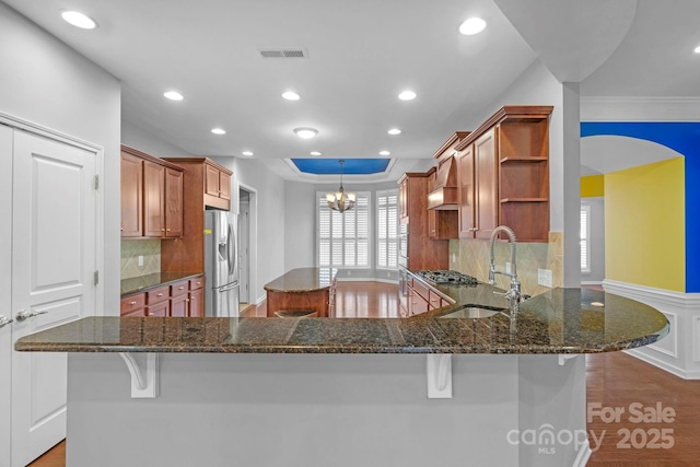 kitchen with visible vents, appliances with stainless steel finishes, a center island, open shelves, and a sink