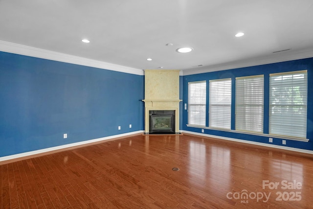 unfurnished living room with a fireplace, ornamental molding, and wood finished floors