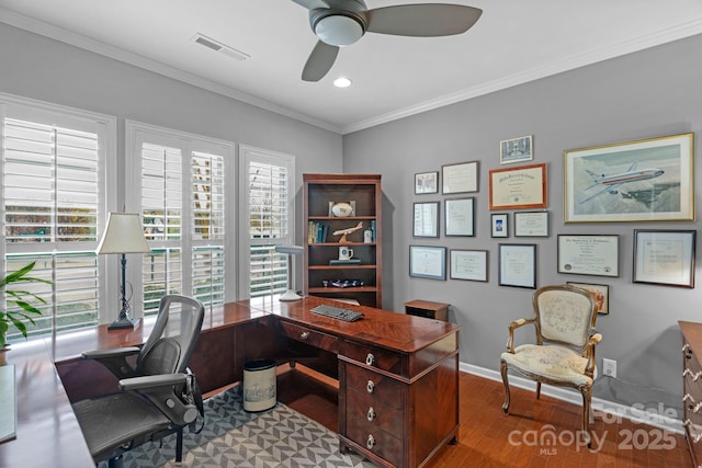 office featuring wood finished floors, visible vents, baseboards, a ceiling fan, and crown molding