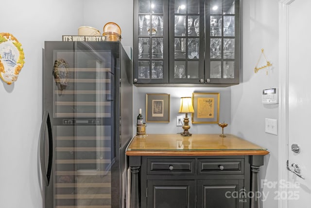 interior space with beverage cooler, butcher block countertops, and glass insert cabinets