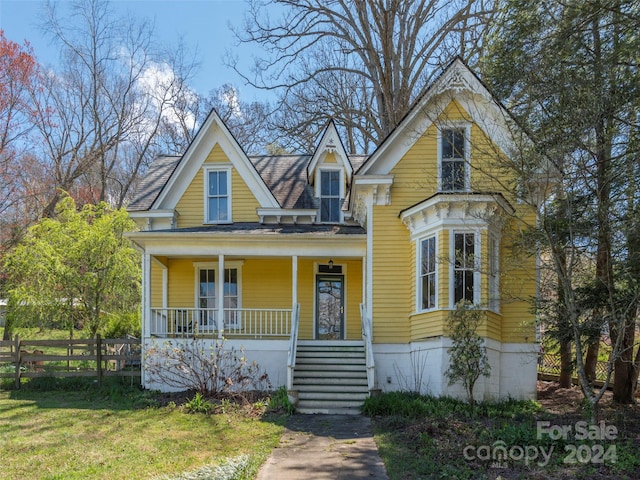 victorian-style house featuring covered porch and a front lawn