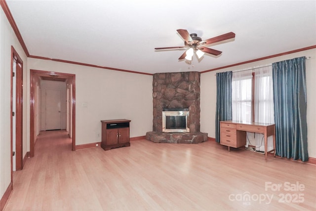 unfurnished living room featuring light wood-type flooring, ceiling fan, crown molding, and a stone fireplace