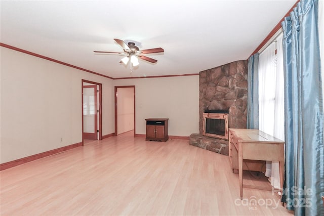 living room featuring ceiling fan, crown molding, a fireplace, and light hardwood / wood-style flooring