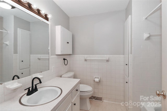 bathroom featuring toilet, tile patterned flooring, tile walls, and vanity