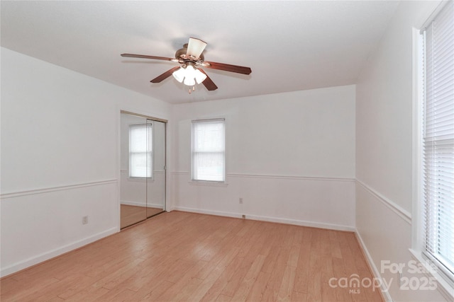 empty room with ceiling fan and light hardwood / wood-style flooring