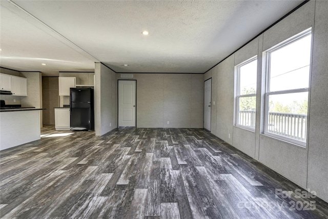 unfurnished living room featuring dark hardwood / wood-style flooring, a textured ceiling, and a wealth of natural light