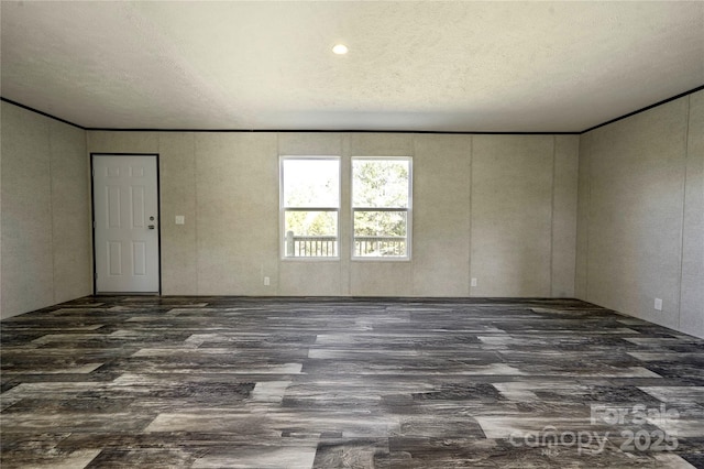 empty room with a textured ceiling and dark hardwood / wood-style floors