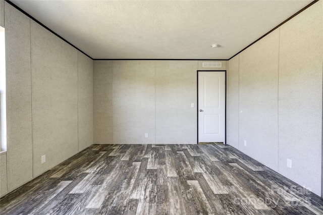 empty room with a textured ceiling and dark hardwood / wood-style floors