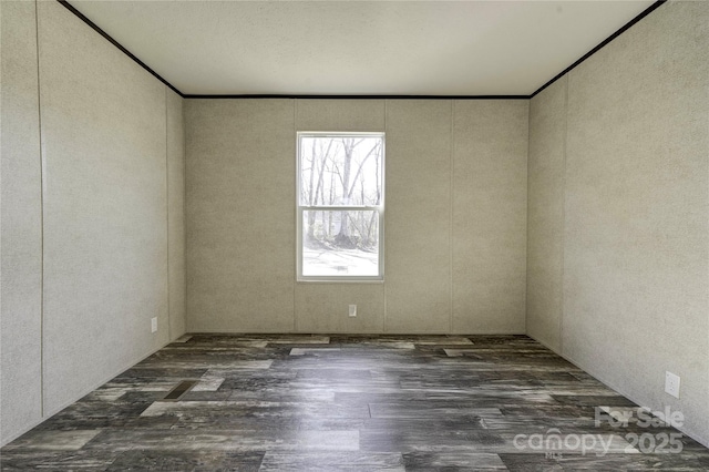 spare room featuring dark hardwood / wood-style flooring and crown molding