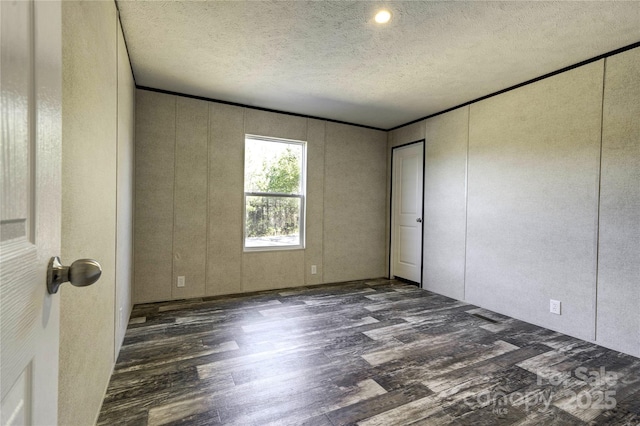 unfurnished room with a textured ceiling, dark hardwood / wood-style floors, and ornamental molding