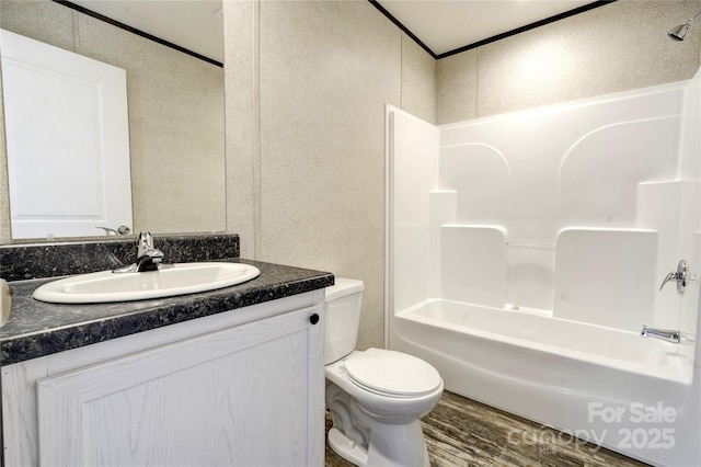 full bathroom with ornamental molding, vanity, shower / bathing tub combination, hardwood / wood-style flooring, and toilet