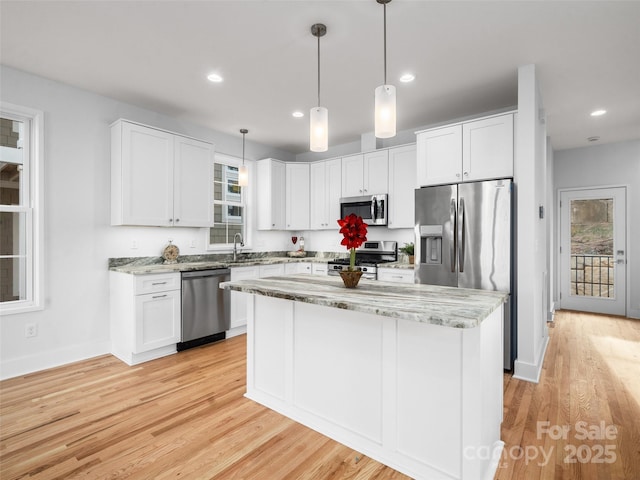 kitchen with white cabinetry, light stone countertops, a sink, and appliances with stainless steel finishes