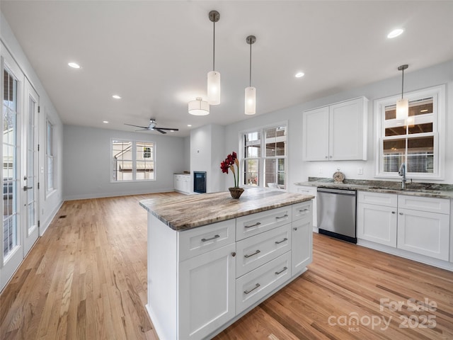 kitchen with white cabinets, hanging light fixtures, dishwasher, light wood-style flooring, and light stone countertops