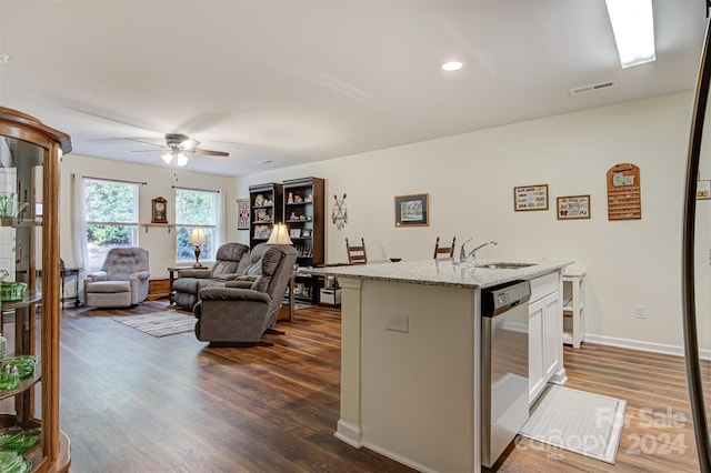 kitchen with dark hardwood / wood-style floors, light stone countertops, white cabinets, stainless steel dishwasher, and a kitchen island with sink