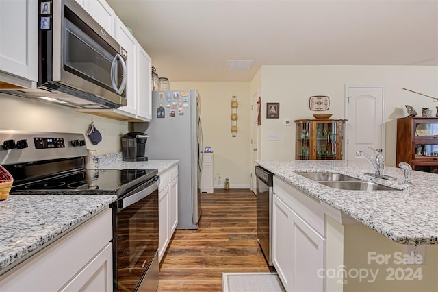 kitchen with white cabinetry, sink, appliances with stainless steel finishes, a kitchen island with sink, and light hardwood / wood-style flooring