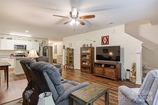 living room with dark wood-type flooring and ceiling fan