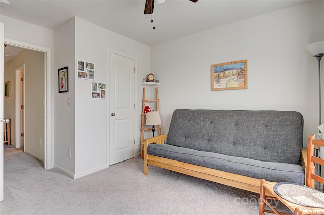 living area featuring light carpet and ceiling fan