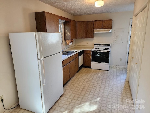 kitchen featuring white appliances, a textured ceiling, and sink