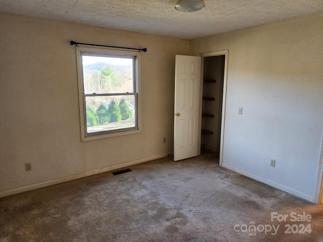 carpeted empty room featuring a textured ceiling