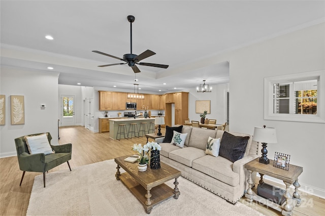 living room with light wood-type flooring, ceiling fan with notable chandelier, and crown molding