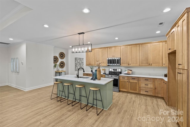 kitchen featuring light hardwood / wood-style floors, a center island with sink, pendant lighting, and appliances with stainless steel finishes