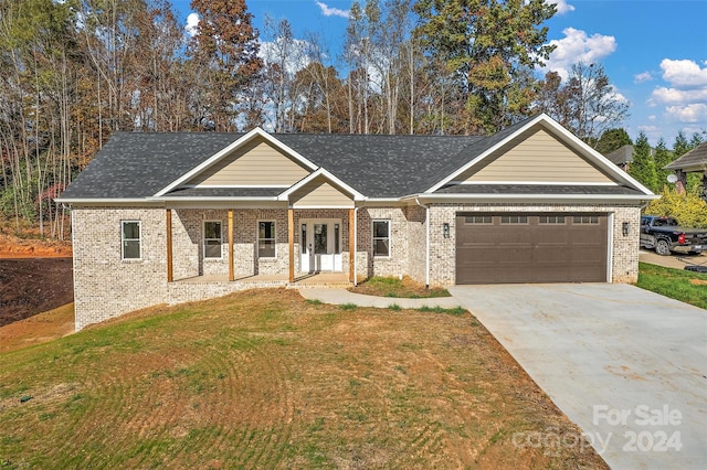 view of front facade with a garage, covered porch, and a front lawn