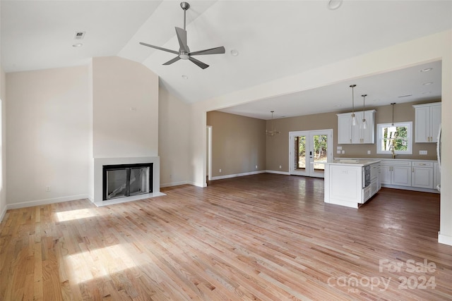 unfurnished living room with lofted ceiling, french doors, ceiling fan, and light hardwood / wood-style flooring