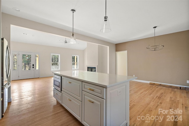 kitchen with decorative light fixtures, light hardwood / wood-style floors, and stainless steel appliances