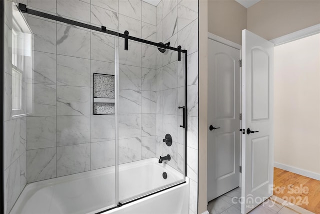 bathroom featuring hardwood / wood-style floors and bath / shower combo with glass door