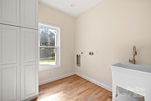 clothes washing area featuring hookup for an electric dryer, cabinets, and light hardwood / wood-style flooring