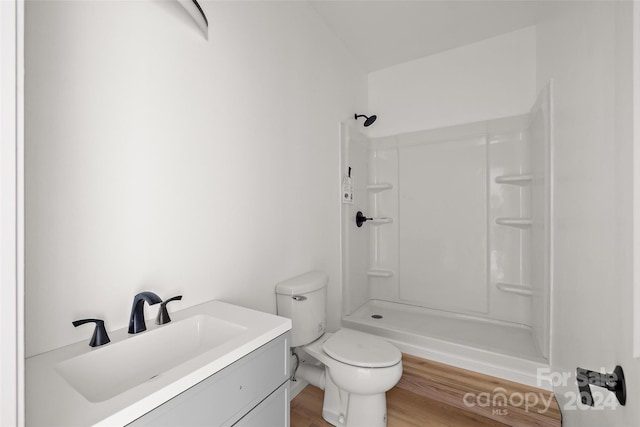 bathroom with a shower, hardwood / wood-style flooring, vanity, and toilet