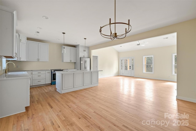 kitchen featuring pendant lighting, sink, light hardwood / wood-style flooring, appliances with stainless steel finishes, and a center island