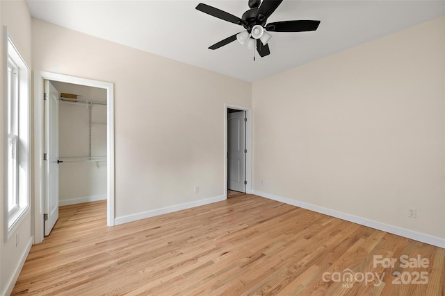 unfurnished bedroom featuring ceiling fan, a spacious closet, light hardwood / wood-style floors, and a closet