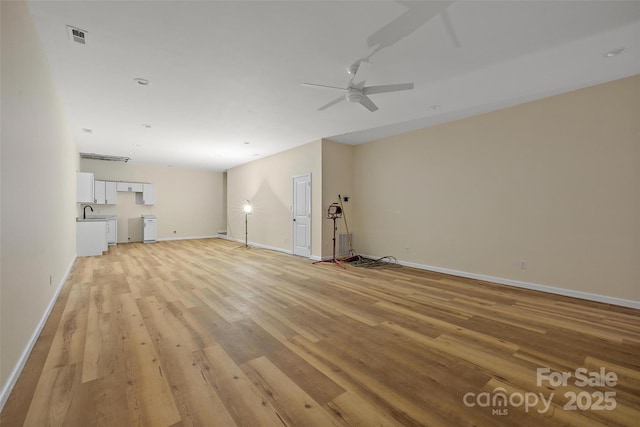 unfurnished living room with sink, ceiling fan, and light hardwood / wood-style flooring