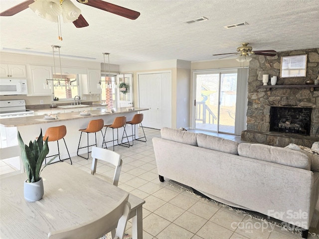 tiled living room with sink, a stone fireplace, and a textured ceiling