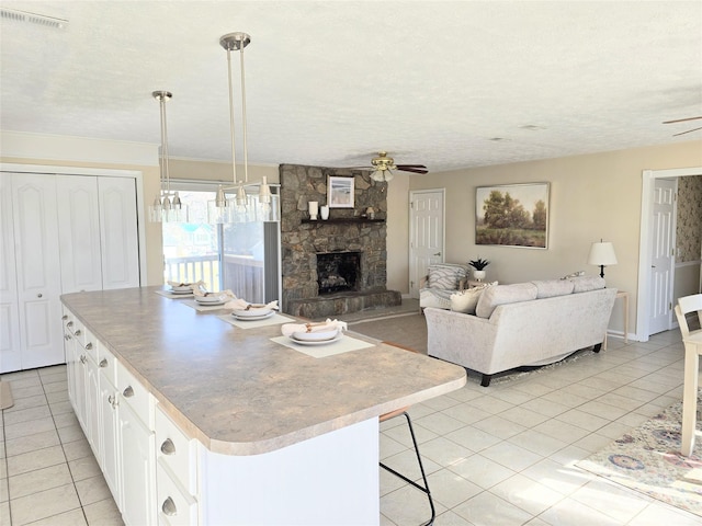 kitchen with ceiling fan, hanging light fixtures, white cabinets, and a center island