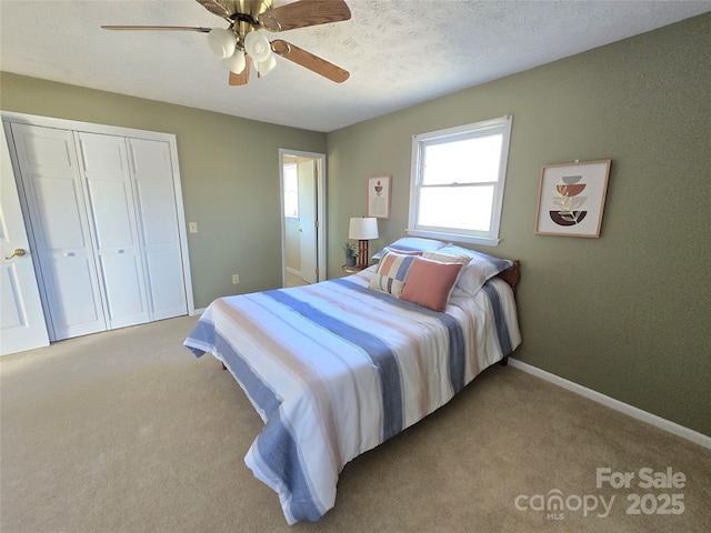 carpeted bedroom featuring ceiling fan, a textured ceiling, and a closet